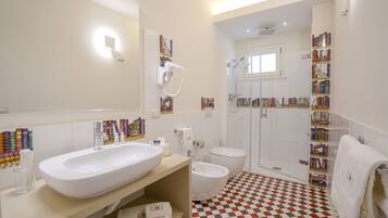 A bathroom with a large white sink, a bidet, a toilet, and a shower area.