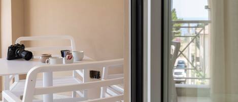 A balcony with a white railing, a table with a camera, a mug, and a cup.