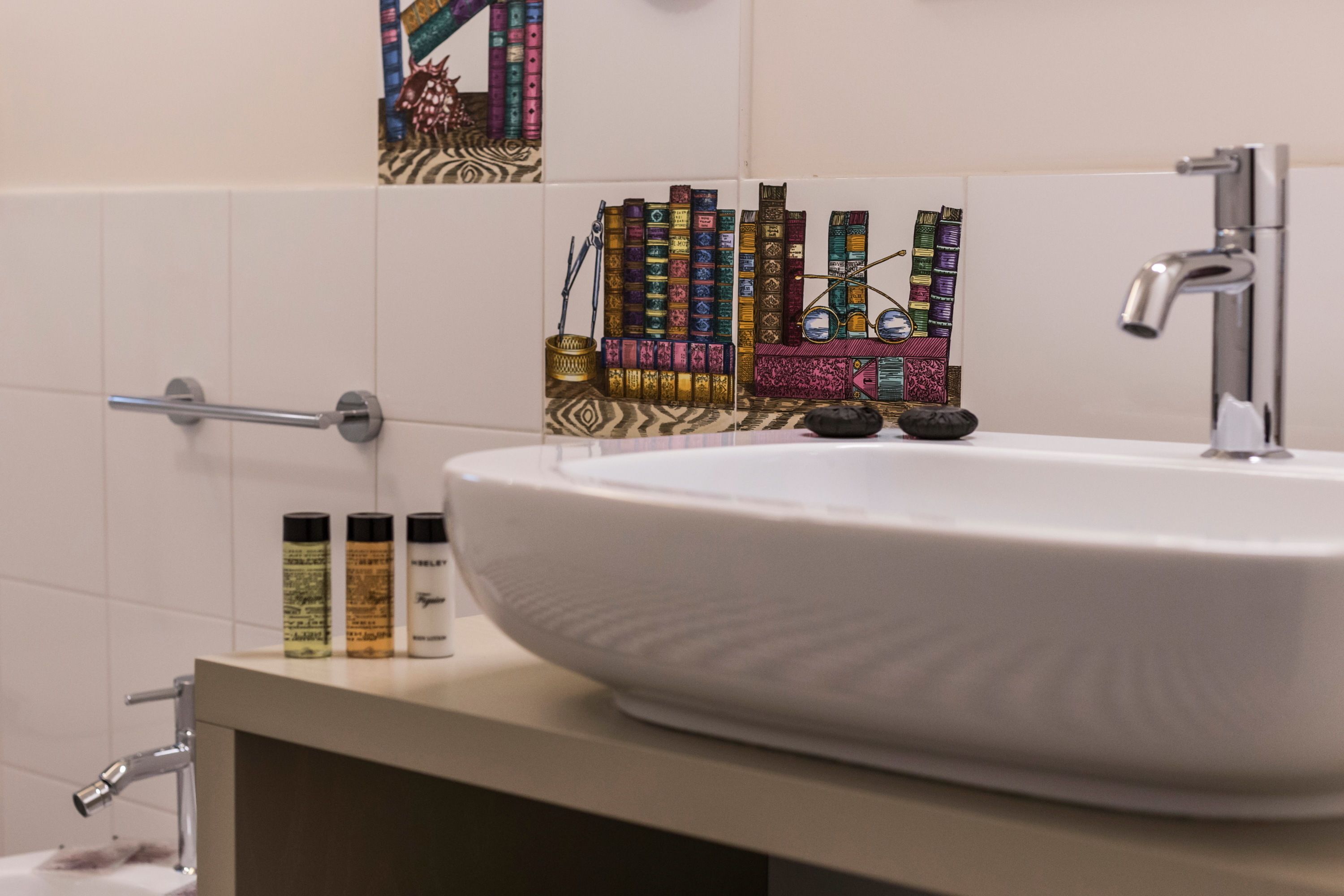 A bathroom with a white sink, a mirror, and a towel rack. There are toiletries on the sink counter.