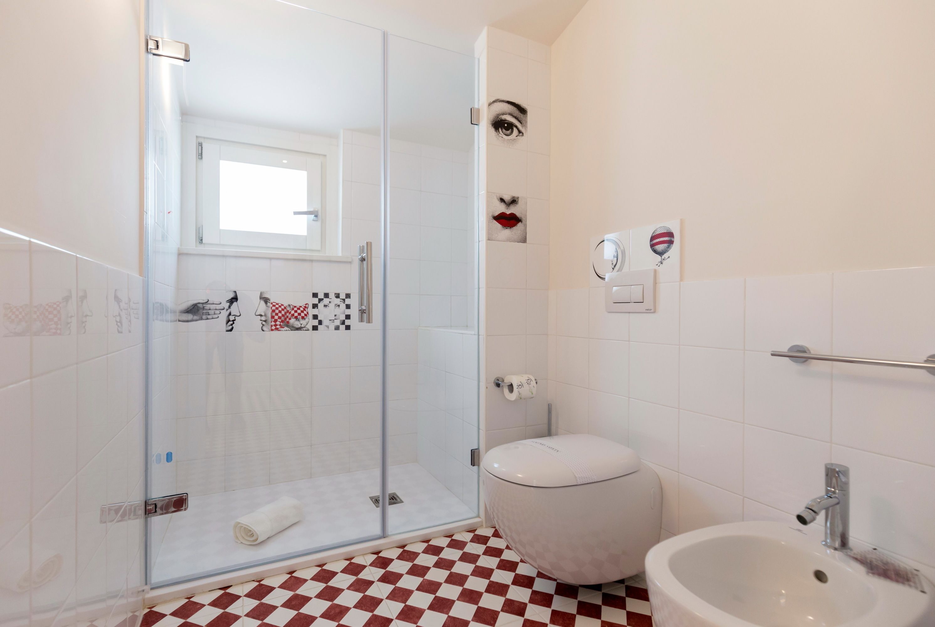 A bathroom with a glass shower enclosure, a toilet, and a sink.