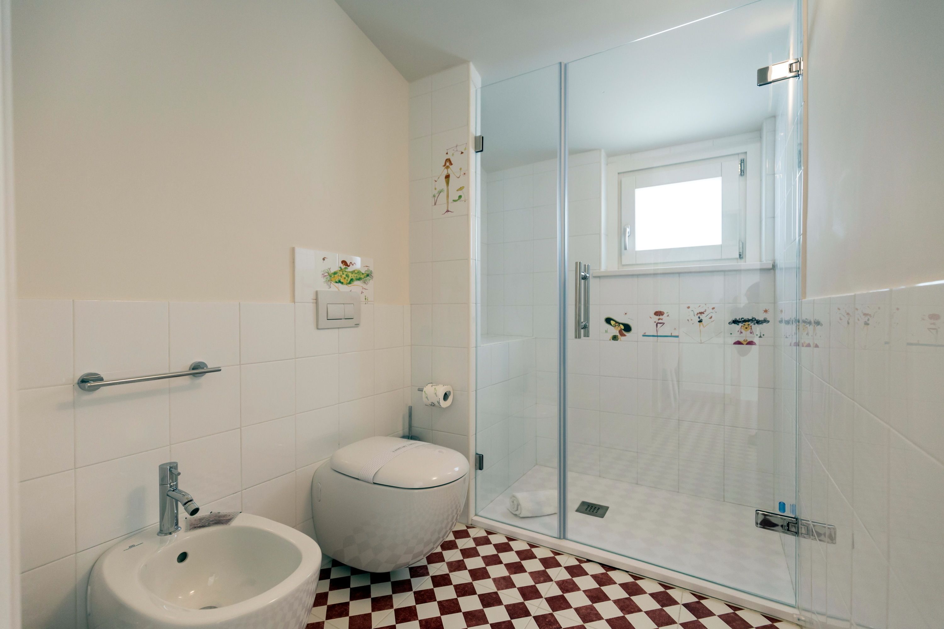Un baño con bidé, inodoro y cabina de ducha de vidrio.