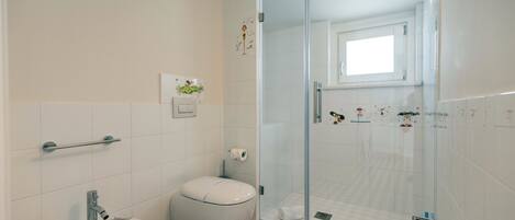 Un baño con bidé, inodoro y cabina de ducha de vidrio.