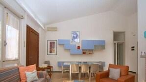 Un espacio habitable compacto con sofá, una silla, una mesita y una kitchenette.