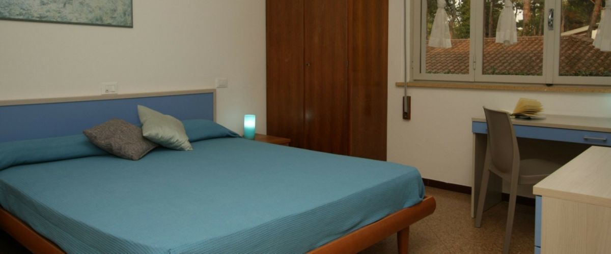 A bedroom with a bed, a desk, a chair, and a wardrobe.