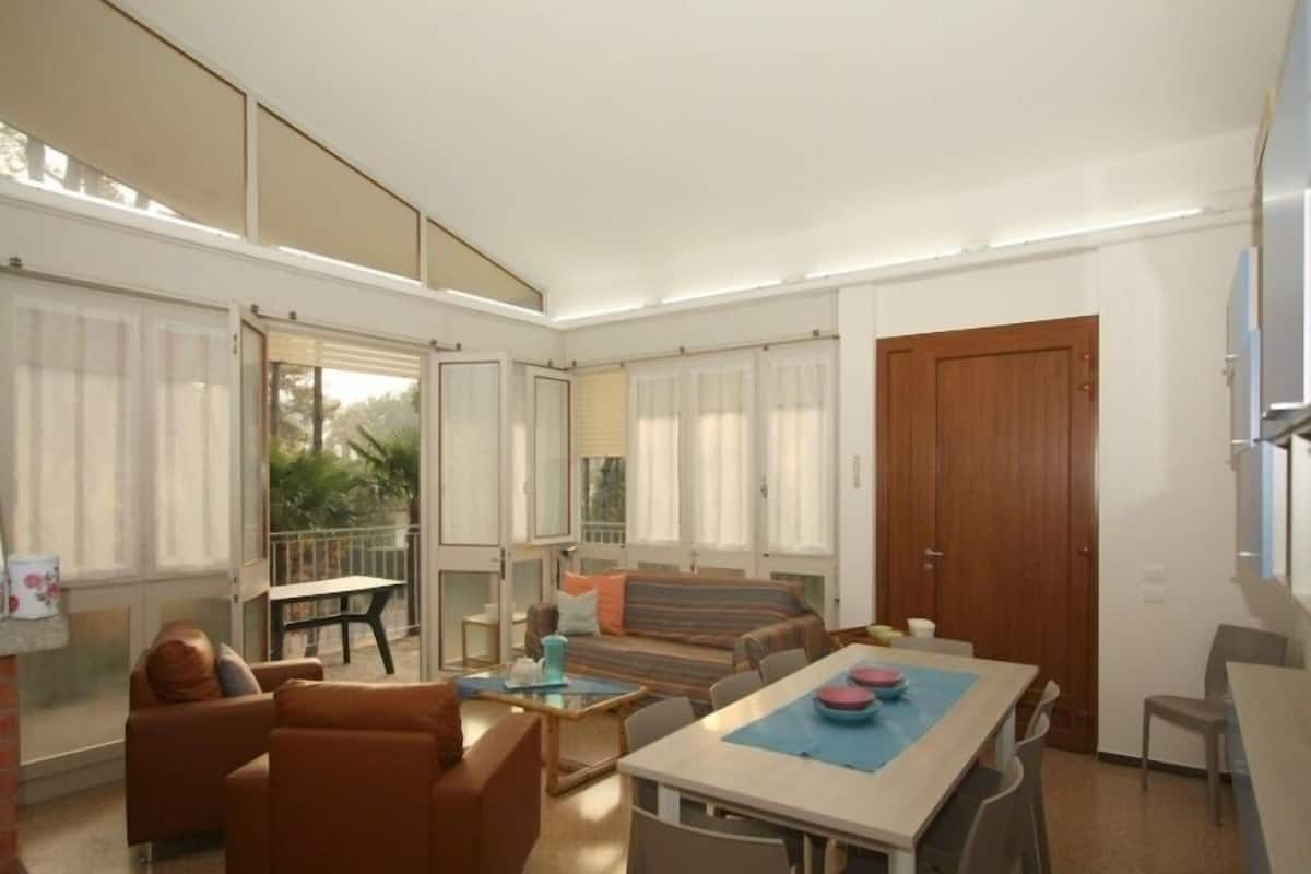 Uma sala de estar ampla com um sofá, uma mesa de jantar e uma varanda.