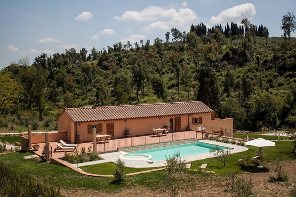 A Mediterranean-style villa with a swimming pool, outdoor seating, and a view of a forested hillside. - Mulino Della Rivolta (Collesalvetti)