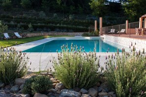 A rectangular swimming pool with a stone deck, surrounded by lavender plants and rocks. - Mulino Della Rivolta (Collesalvetti)
