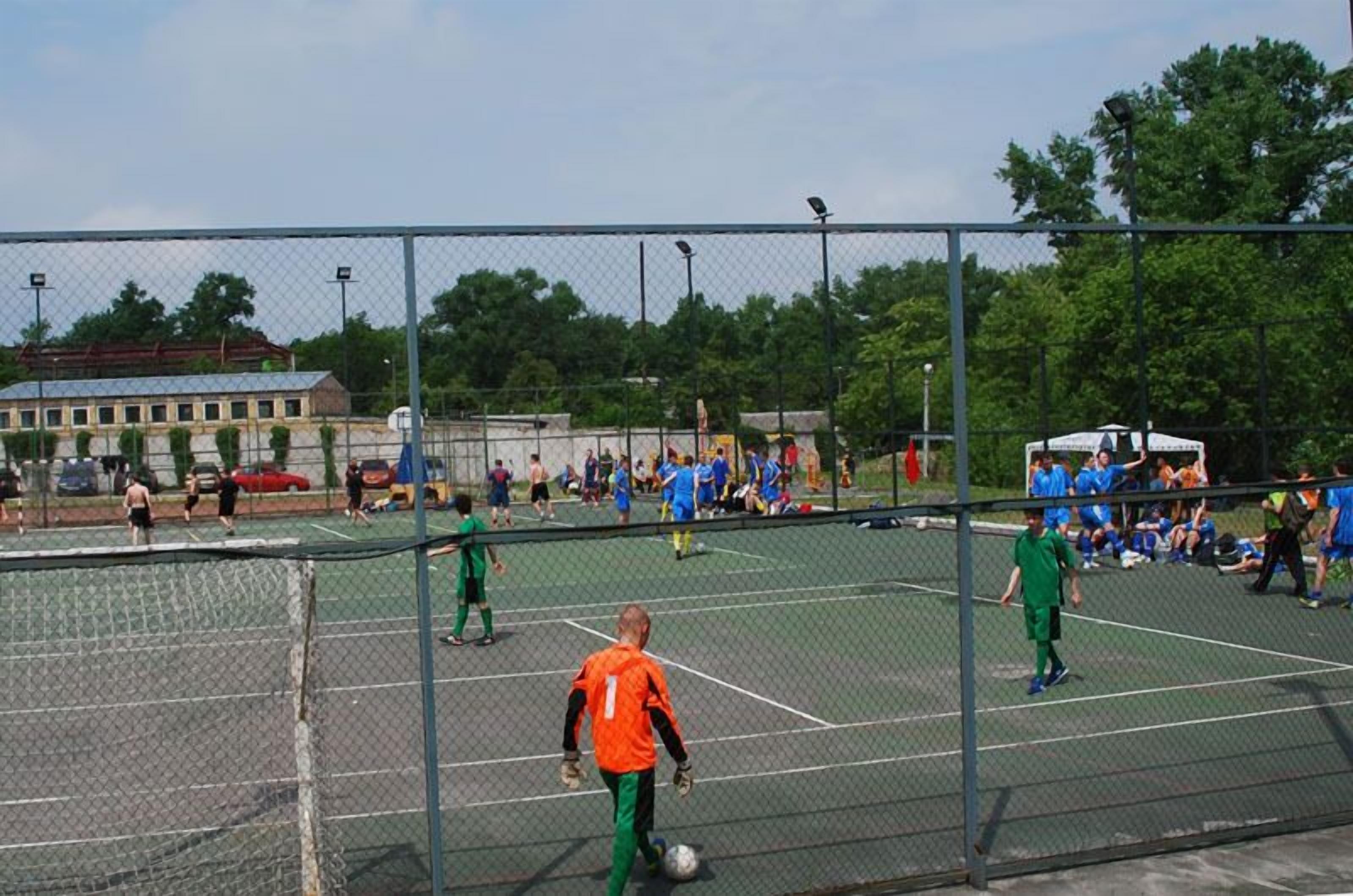 Un terrain de sport extérieur doté de plusieurs courts de tennis, entouré d’une clôture en treillis métallique.