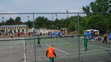 Un terrain de sport extérieur doté de plusieurs courts de tennis, entouré d’une clôture en treillis métallique.