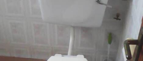 Eine Standardtoilette mit weißem Sitz und Tank in einem Badezimmer mit Fliesenboden und gemusterten Wänden.