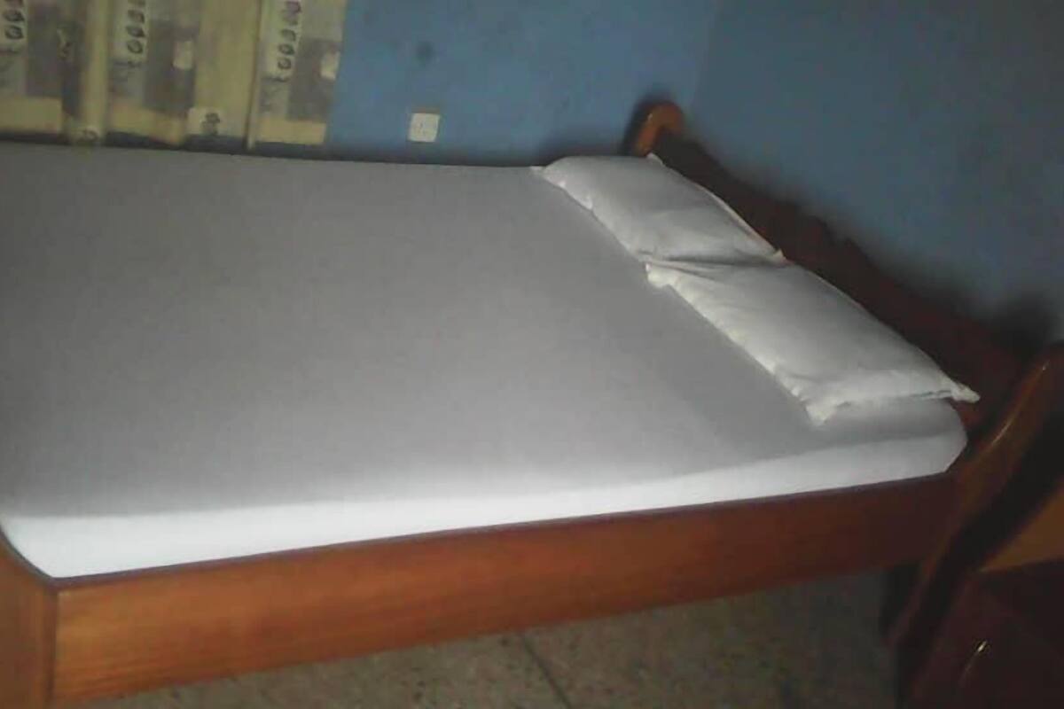 A single bed with a wooden frame and white bedding in a room with blue walls.