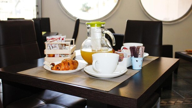 Desayuno con cruasanes, café y té sobre una mesa en una habitación con ventanas amplias.
