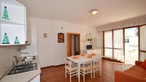 A compact kitchen with a gas stove, white cabinets, and a dining table with chairs.