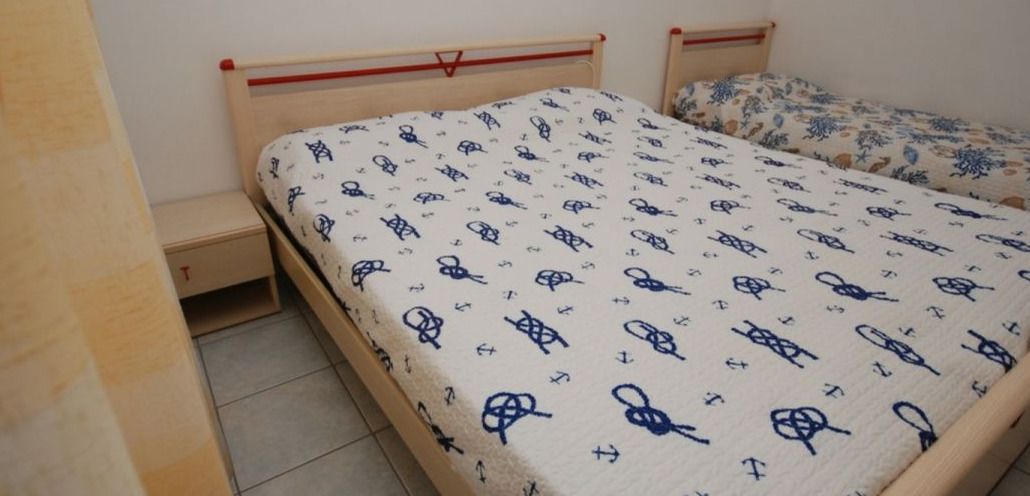 Ein Schlafzimmer mit zwei Einzelbetten, beide mit gemusterten Bettdecken. An jedem Bett steht ein kleiner Nachttisch und darunter befindet sich eine Schublade.
