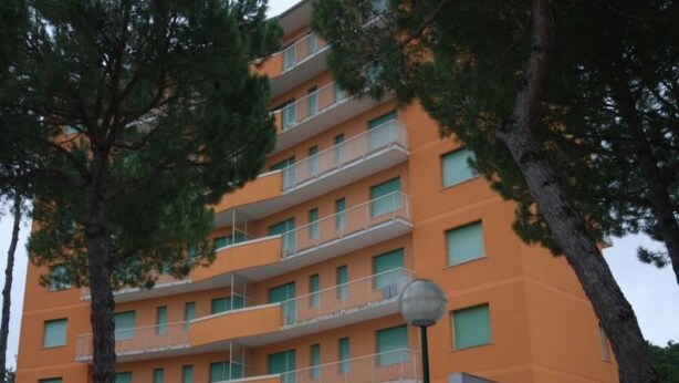A multi-story building with balconies and a sign indicating it is a hotel. - Arcobaleno (Lignano Sabbiadoro)
