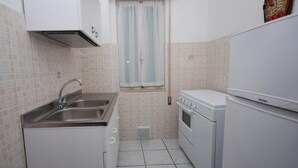 A compact kitchen with a sink, stove, and refrigerator. - Arcobaleno (Lignano Sabbiadoro)