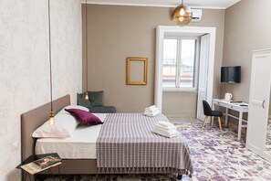 A bedroom with a bed, bedside table, and a desk with a chair. - N'Art Suites Napoli (Naples)