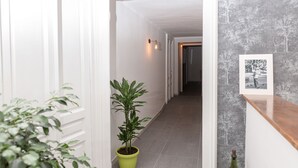A hallway with a potted plant, a framed picture on the wall, and a wooden counter. - N'Art Suites Napoli (Naples)