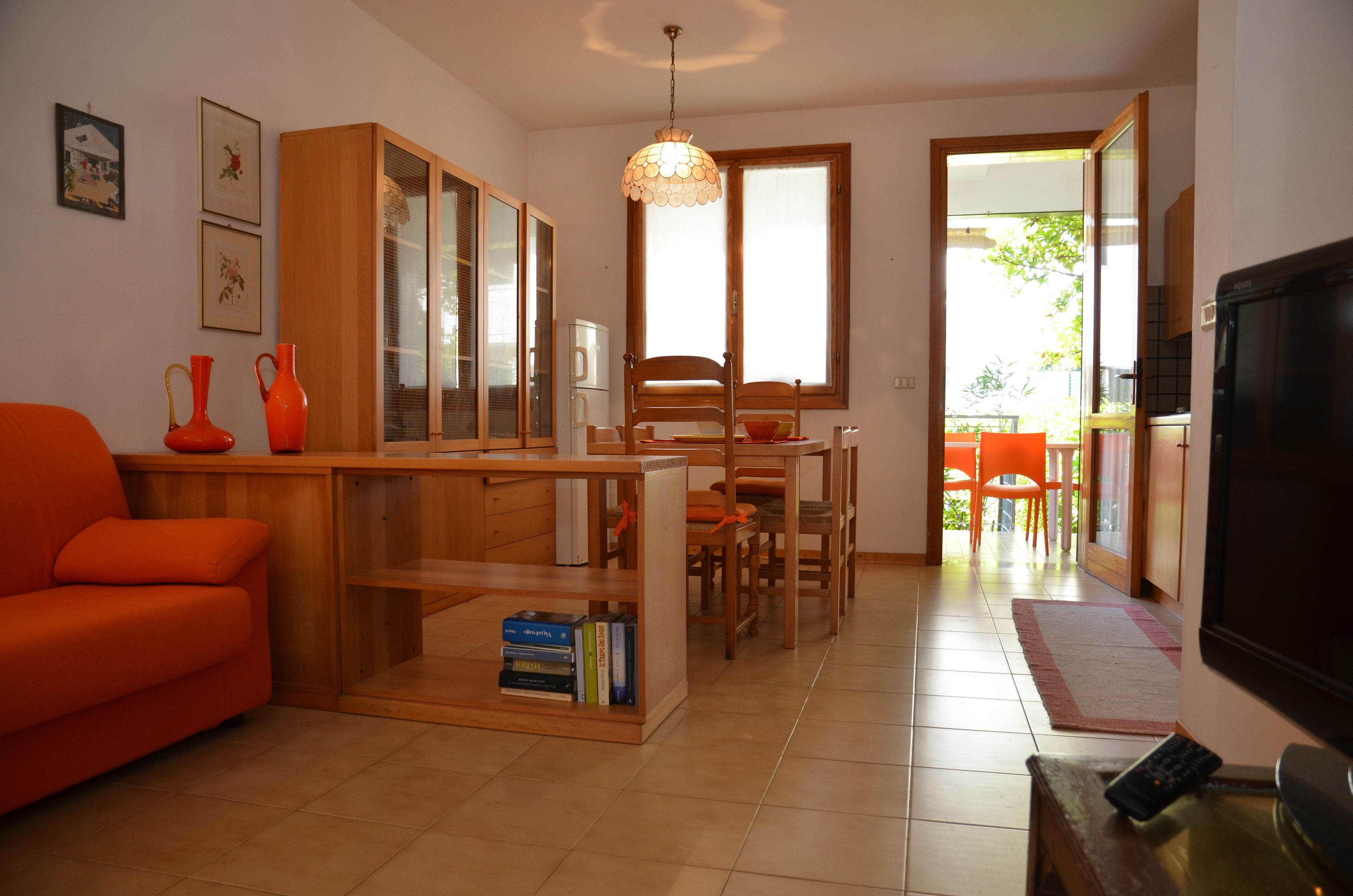 A living room with a sofa, wooden furniture, a dining table with chairs, and a TV.