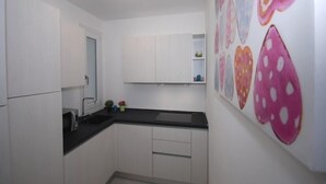 A small kitchen with white cabinets, a black countertop, and a ceiling light. - Arketipi (Lignano Sabbiadoro)