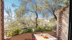 An outdoor patio with a table and chairs, a bottle of wine, and a basket of fruit. - Levantin Inn 1,3 Room N4 Sea Side (Sveti Stefan)