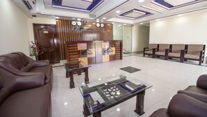 A reception area with a wooden reception desk, leather sofas, and a glass coffee table. - Hotel Ali Plaza (Sylhet)