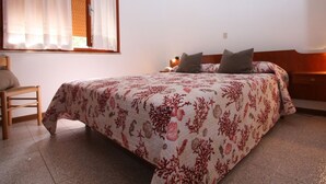 A bedroom with a bed, a chair, and a window with curtains. - Villa Capinera (Lignano Sabbiadoro)