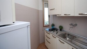 Eine kompakte Küche mit weißen Schränken, einer Edelstahlspüle und einer kleinen Arbeitsfläche.