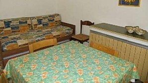 Una habitación pequeña y acogedora con una cama, una silla, una mesa y un cuadro en la pared.