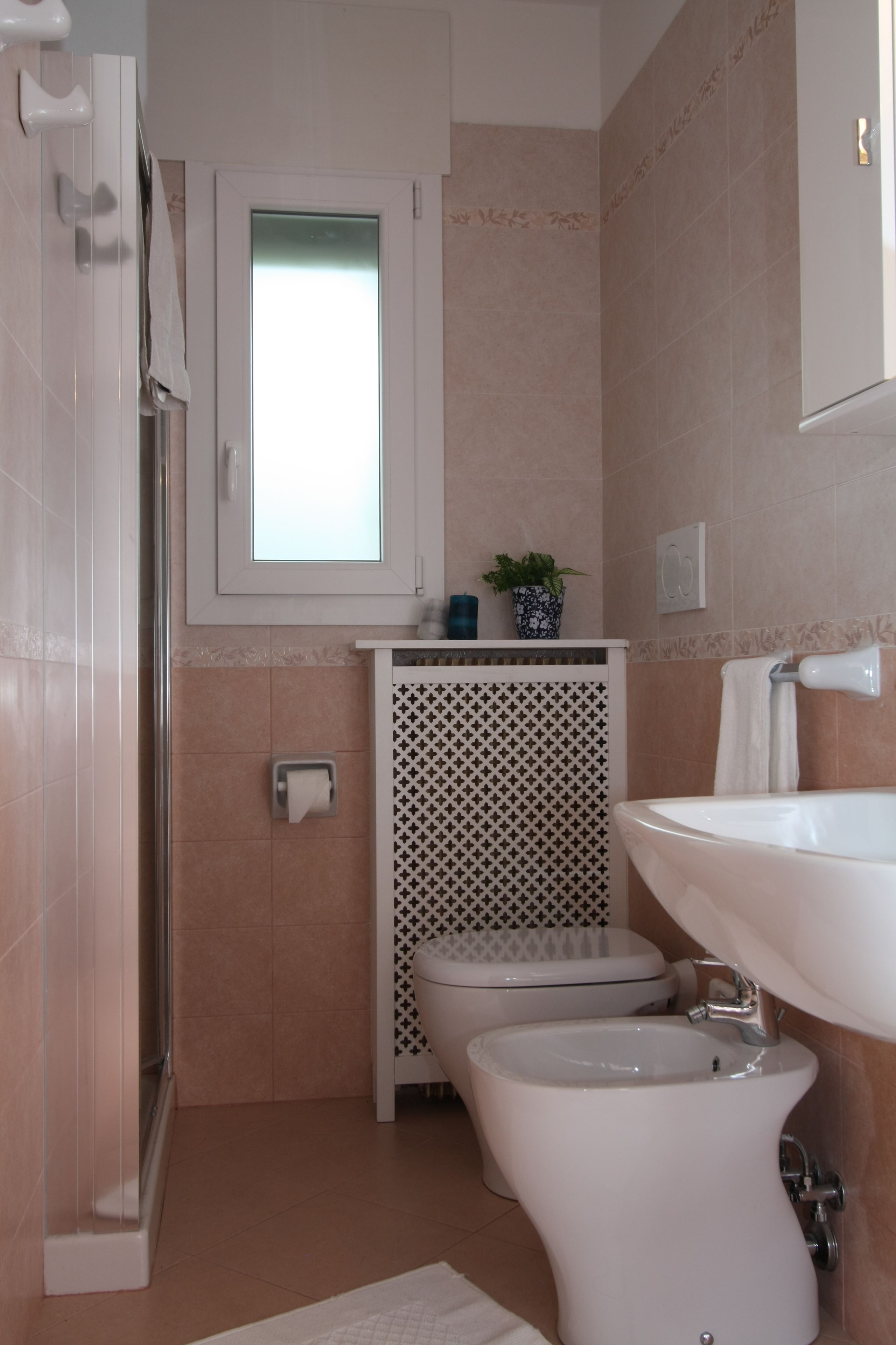 A bathroom with a shower, toilet, bidet, and sink.