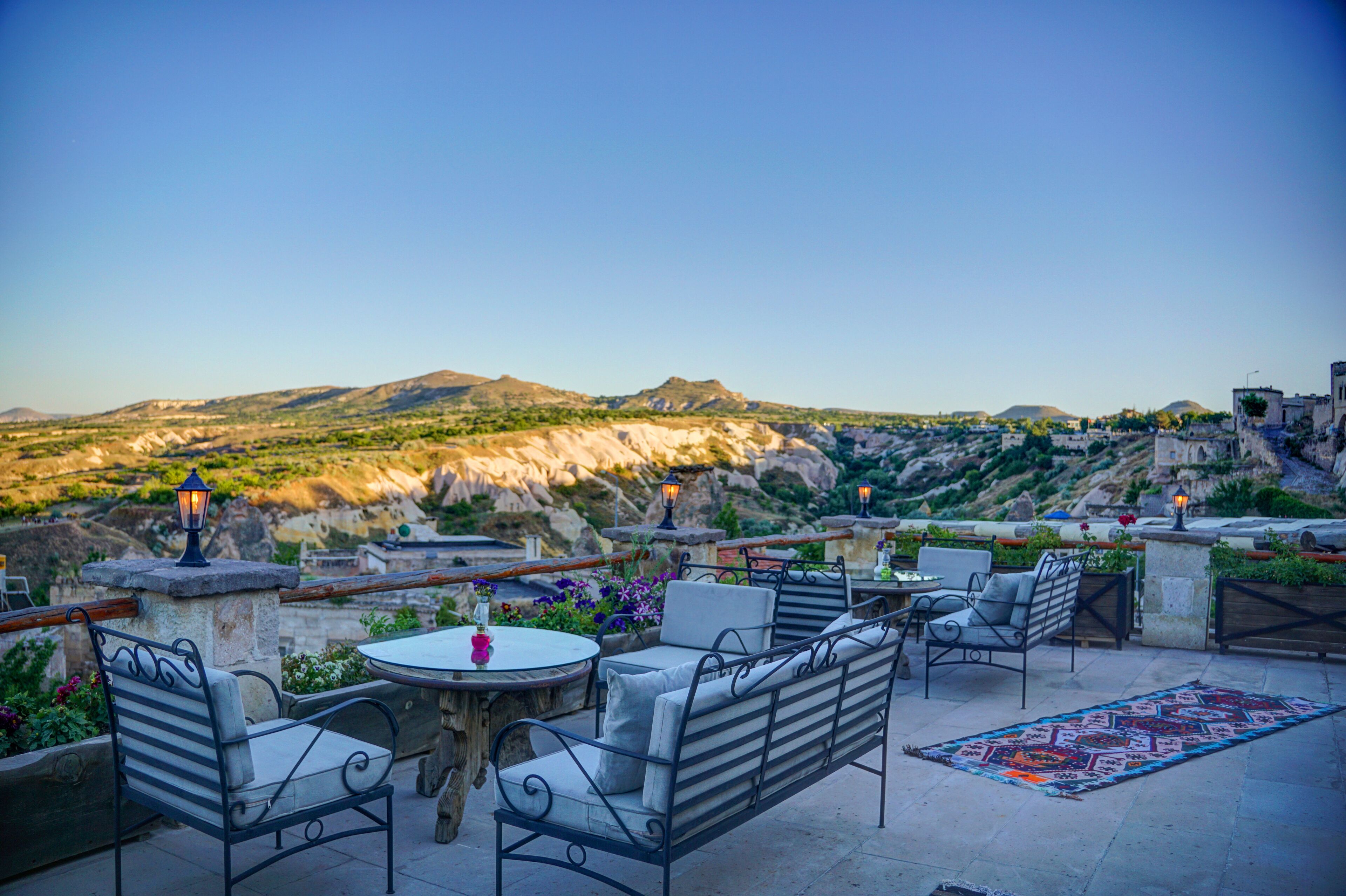 An outdoor seating area with tables and chairs, overlooking a mountainous landscape.
