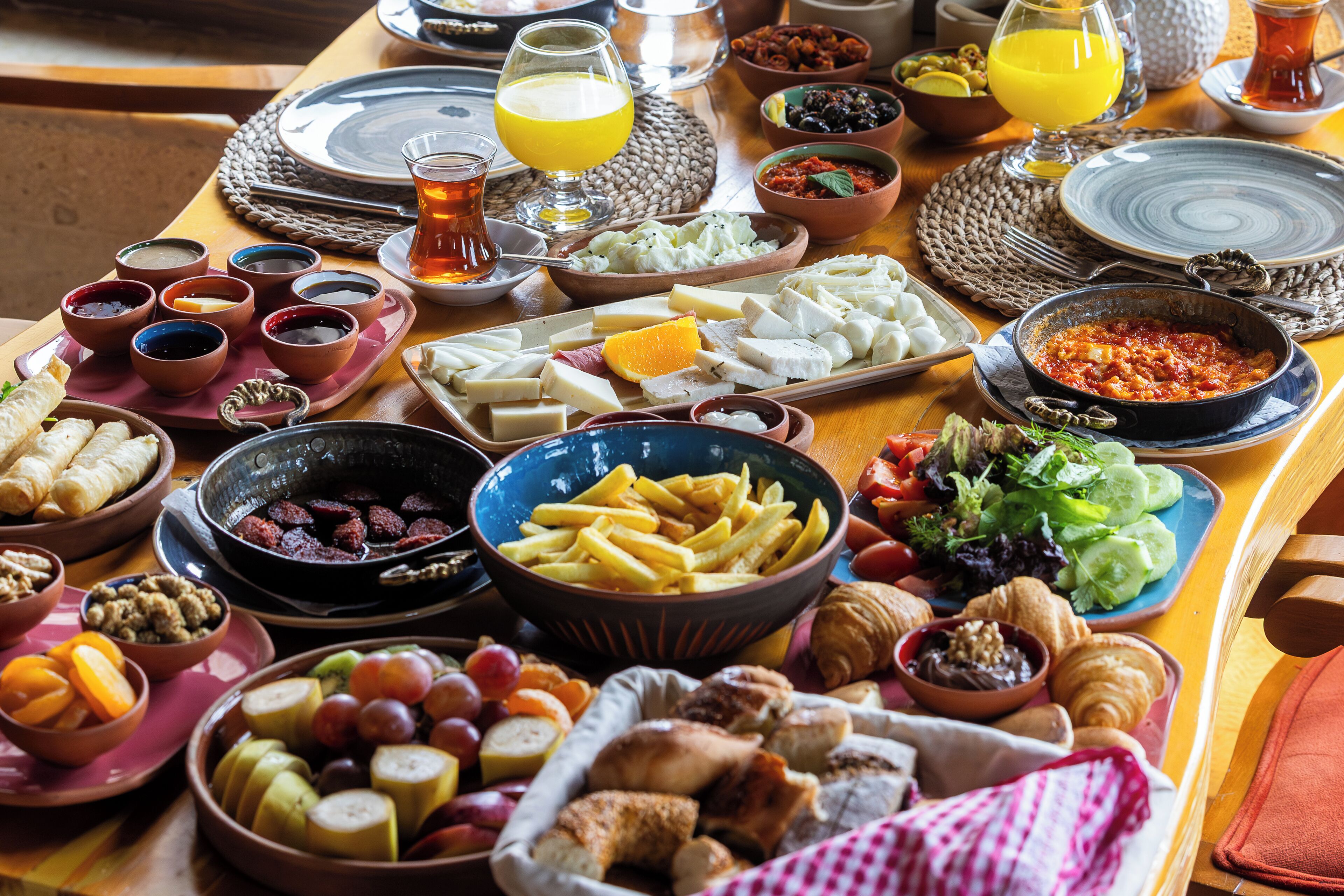 Una mesa con diversos alimentos y bebidas, como queso, frutas y pan.