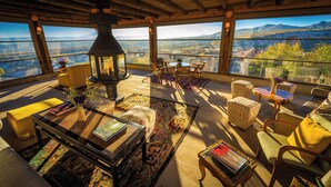 Uma varanda espaçosa com lareira, assentos confortáveis e vista para as montanhas.