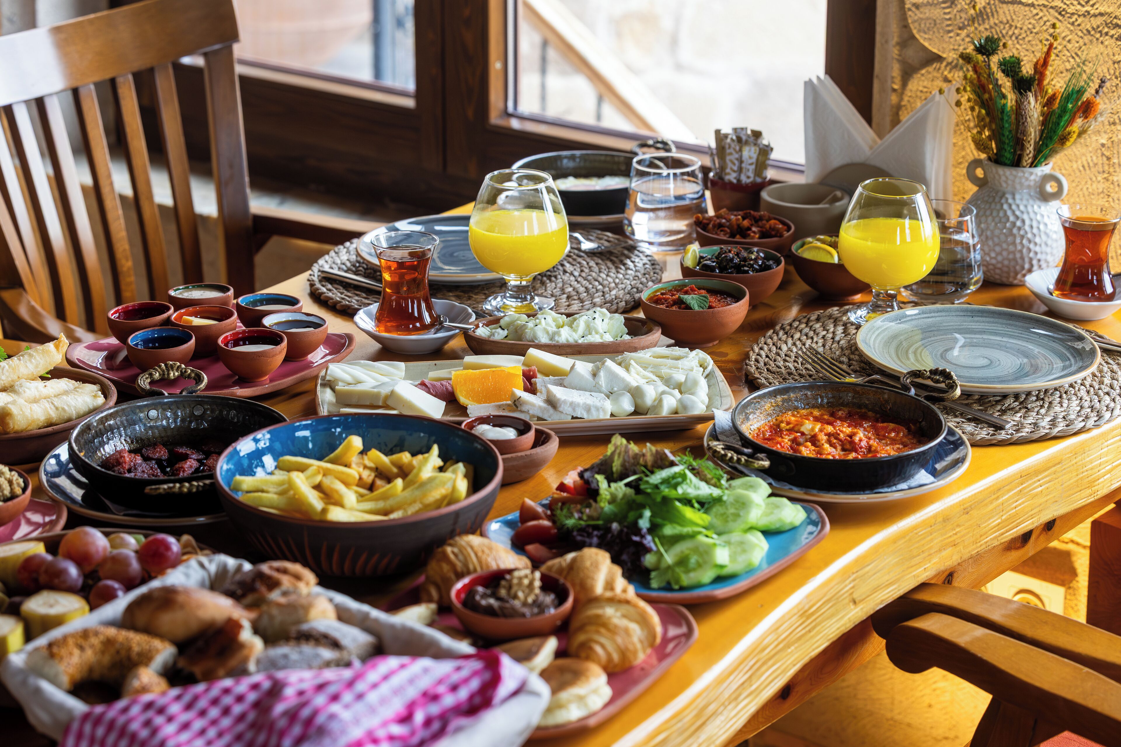 A breakfast spread with various dishes and beverages on a wooden table.