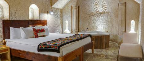 A bedroom with a wooden bed, a round bathtub, and a chair.