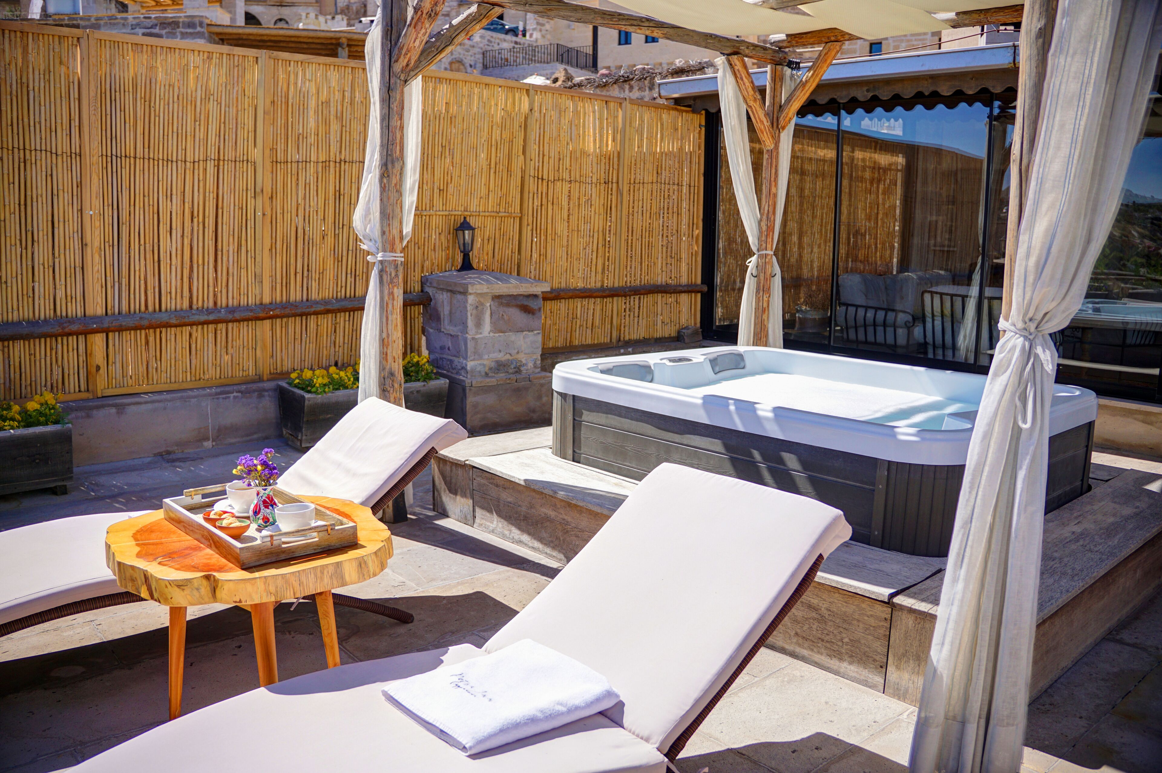 Terraza en la azotea con sillones de descanso, bañera de hidromasaje y una mesa de madera con una bandeja de comida y bebidas.