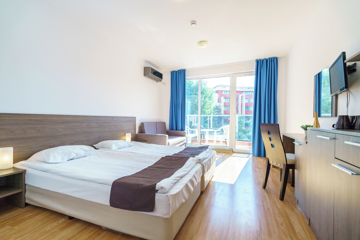 Une chambre d’hôtel avec un grand lit, un bureau, une chaise et un téléviseur.