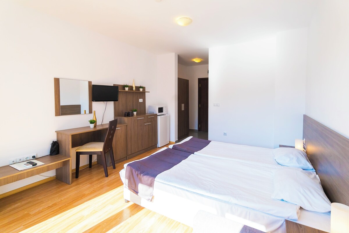 Une chambre d’hôtel comprenant un lit, un bureau, une chaise, une télévision et une armoire.