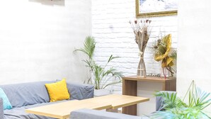 Ein modernes Wohnzimmer mit einem grauen Sofa, einem Holztisch und einer Wand aus weißen Ziegeln.