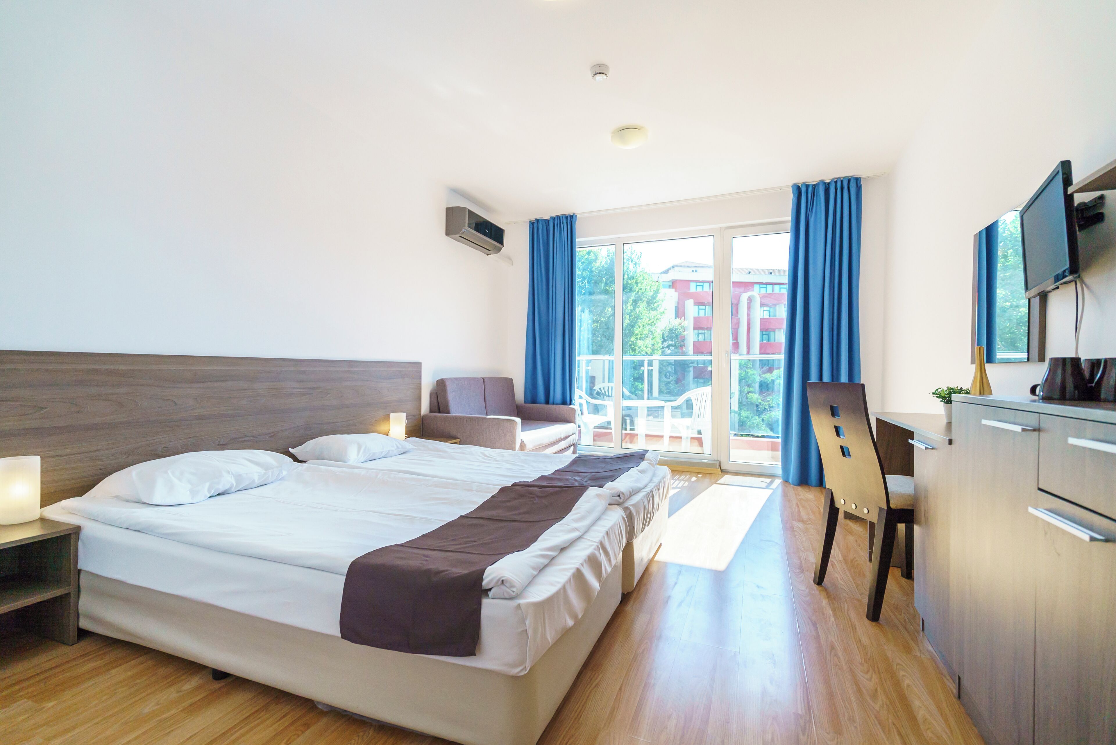 Una habitación de hotel con una cama grande, un escritorio, una silla y un televisor.
