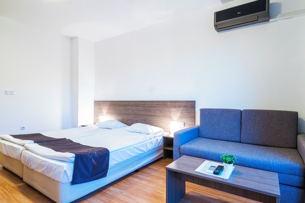Une chambre d’hôtel équipée d’un lit, d’un canapé, d’une table de chevet et d’un climatiseur fixé au mur.