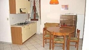 Une cuisine de taille réduite comprenant une table et des chaises, un réfrigérateur et une cuisinière.