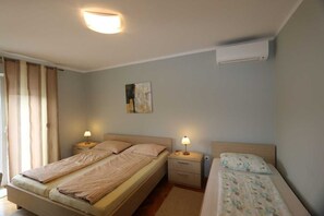 Quarto com cama, mesas de cabeceira, luminária, pintura e ar condicionado.