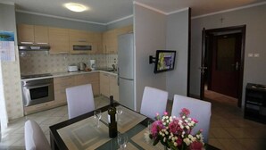 Une cuisine moderne avec un coin repas, un réfrigérateur, un four et une table à manger avec des chaises.