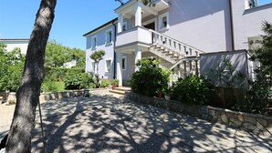 Une maison à deux étages avec un escalier en pierre, une véranda et une allée gravillonnée.