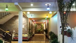 A hotel lobby with a central staircase, a seating area, and a garden view. - Hotel Vamdev Fort (Pushkar)