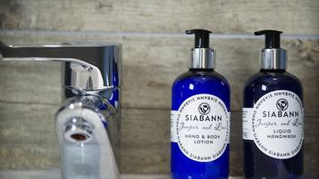 A bathroom with a chrome faucet and two bottles of Siabann hand and body lotion.