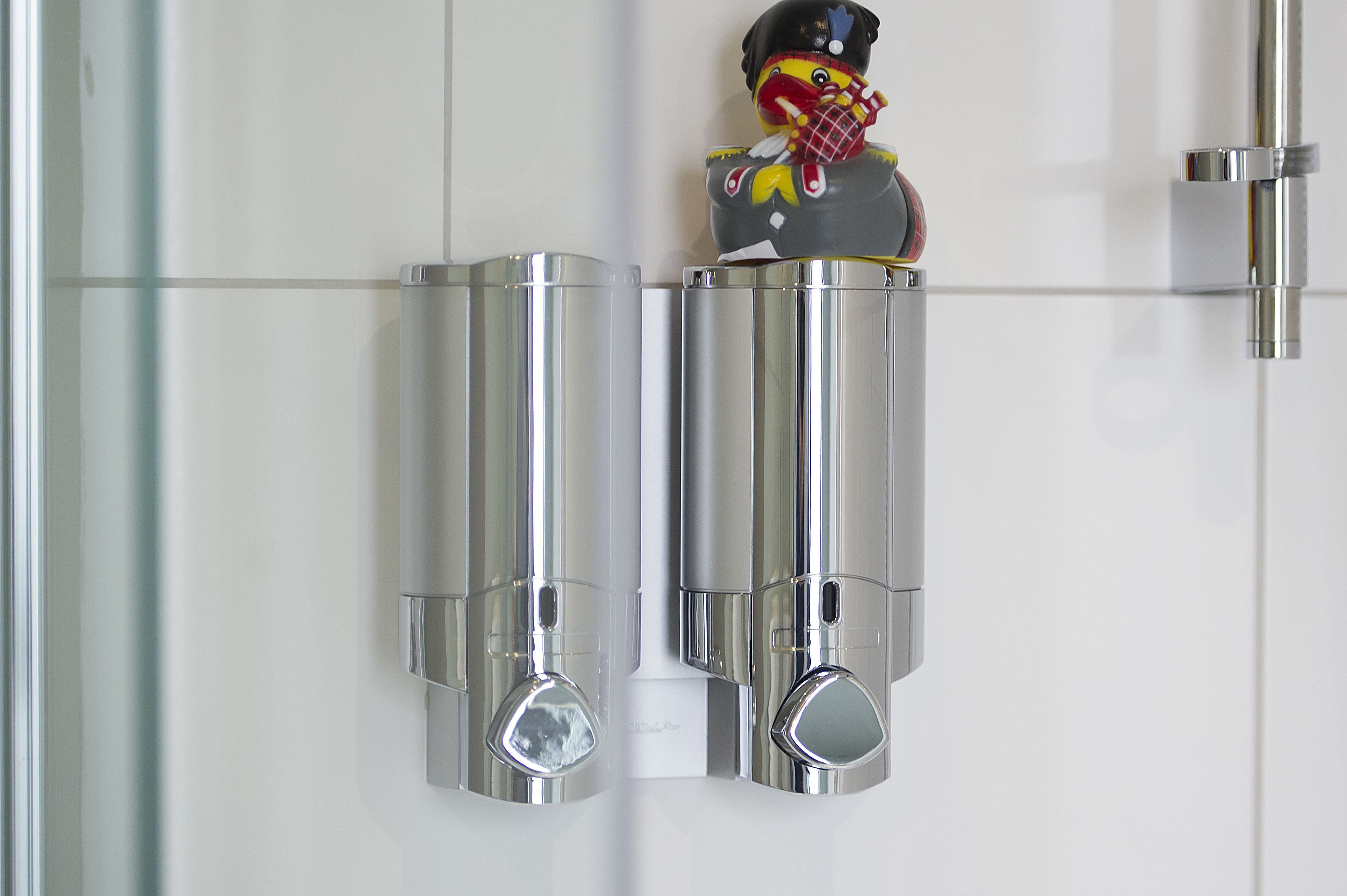 A bathroom with chrome fixtures and a decorative toy figure on the wall.