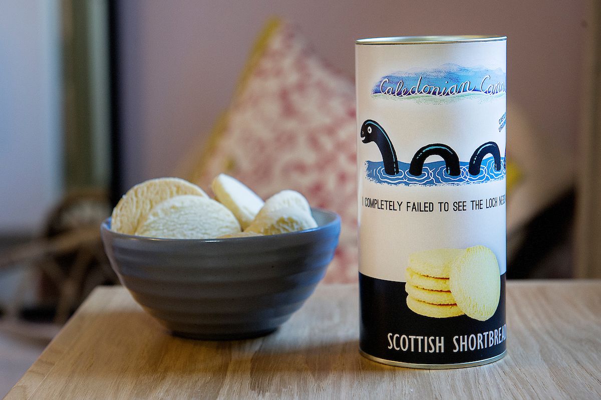 Una lata de galletas escocesas junto a un tazón de helado.