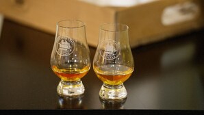 Two glasses of whisky on a table with a box in the background.
